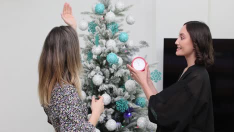 two women decorating a christmas tree for the holidays