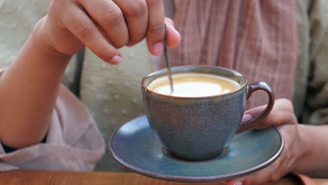 una mujer agita su café con una cuchara