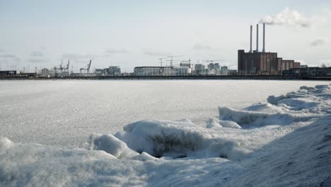 frozen sea on coast city in cold, sunny winter day
