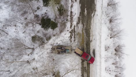 pickup truck with trailer of snowmobiles reversing and pulling out onto road in winter snow