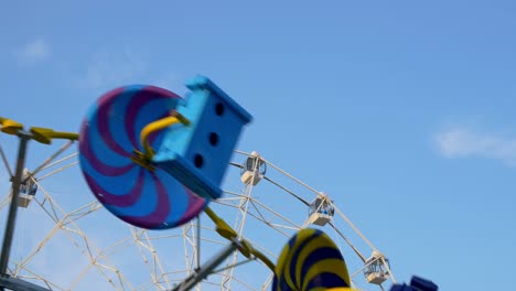 un carrusel en un parque de atracciones, una rueda de observación en una feria, un carrusel rápido está girando en primer plano, una ruedas del diablo en el fondo contra el cielo. atracciones irreconocibles