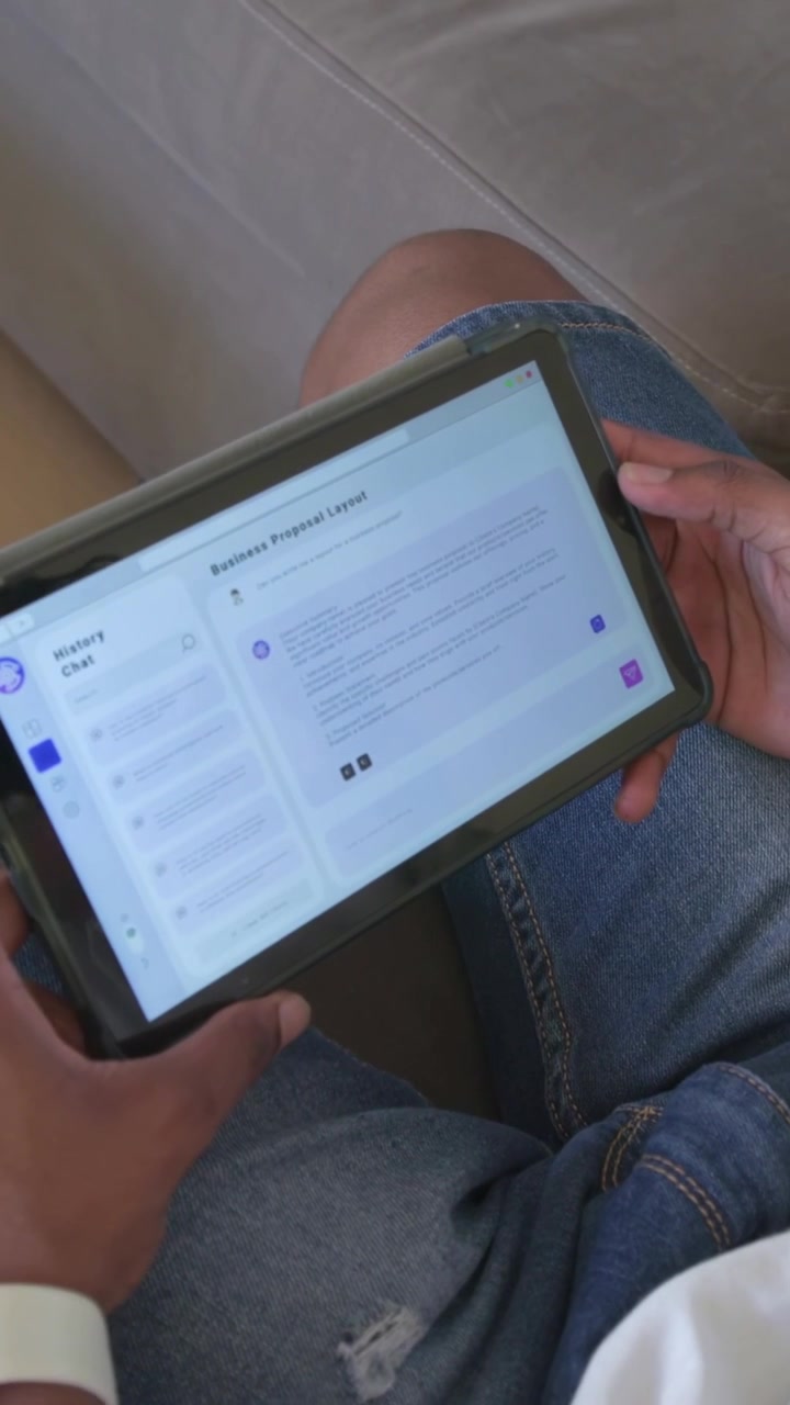 Vertical video: Viewing proposal, man in shorts scrolling tablet on sofa, showing watch, earphone