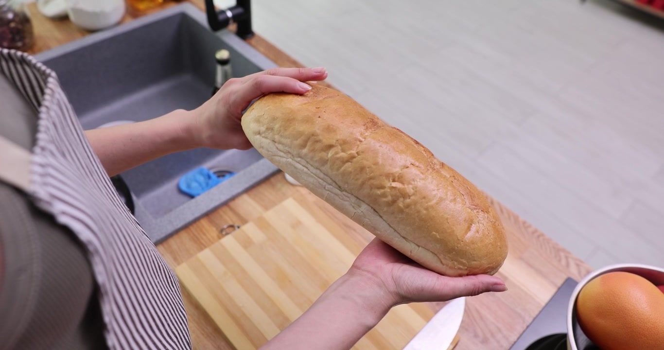 Baker holds freshly baked bread turning loaf in kitchen