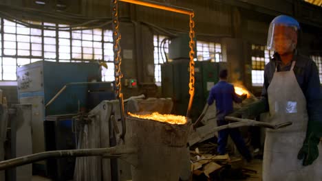 trabajador masculino que lleva metal fundido en el taller 4k