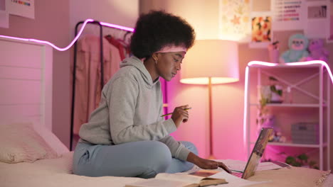 young woman studying on her laptop in her bedroom at night