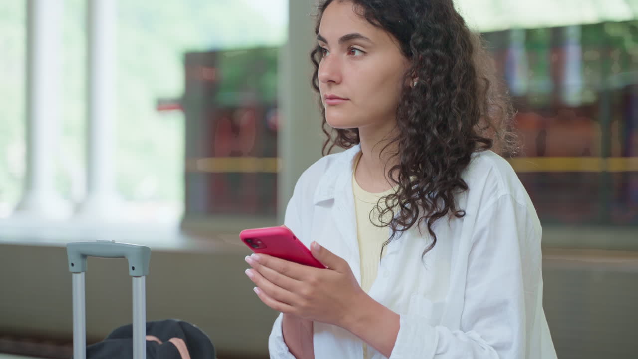 una joven usando un teléfono inteligente en el aeropuerto.
