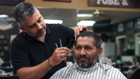 a barber skillfully trims and shapes the hair of a client in a cozy barbershop. the atmosphere is welcoming as the customer appreciates the personalized attention and care.