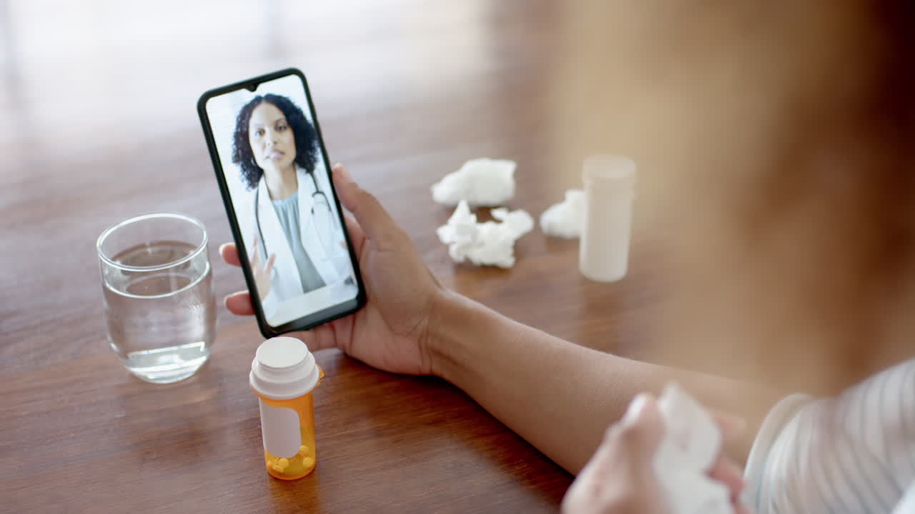 Doctora birracial y paciente en casa en videollamada por smartphone, en cámara lenta.