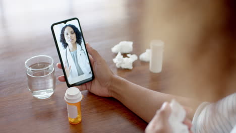 Biracial-female-doctor-and-sick-patient-at-home-having-smartphone-video-call,-slow-motion