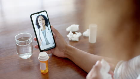 doctora biracial y paciente enfermo en casa haciendo una llamada de video con el teléfono inteligente, en cámara lenta