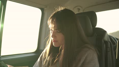 traveling woman reading book in van at sunset