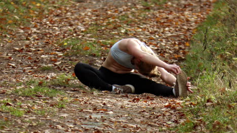 a woman doing warm-up stretches before going for a run through a nature reserve