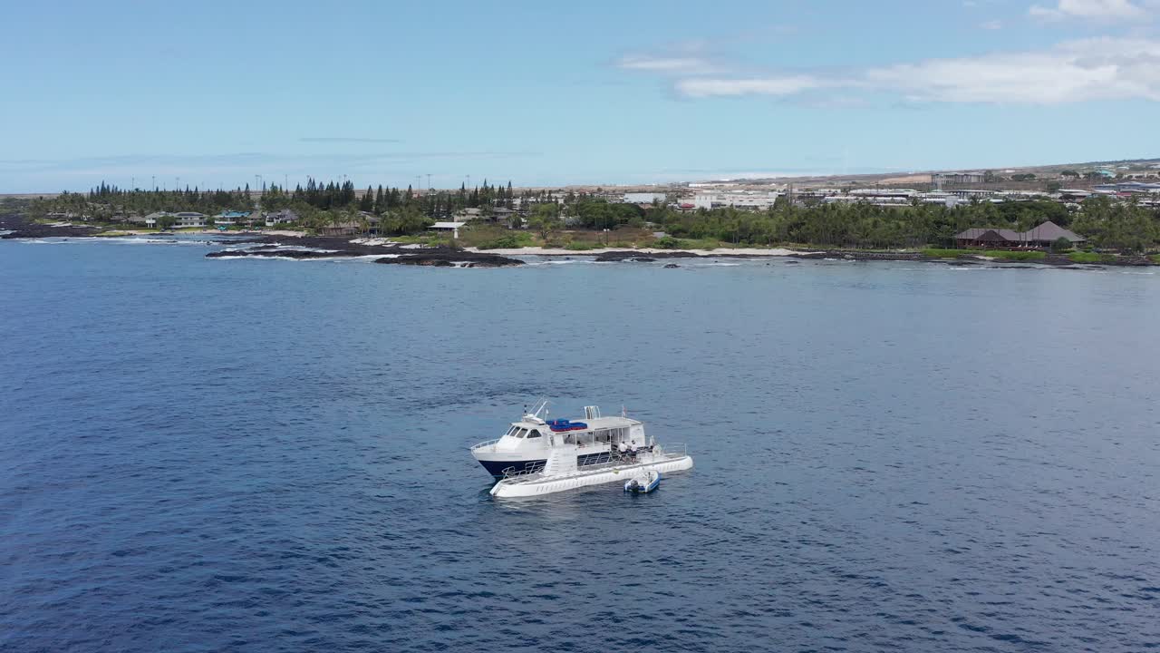 Aerial push-in close-up shot of people disembarking a ferry boat and boarding a submarine off the shores of Kailua-Kona, Hawai'i