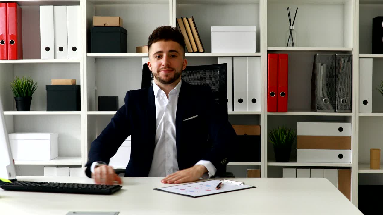 young businessman showing thumb up in light office