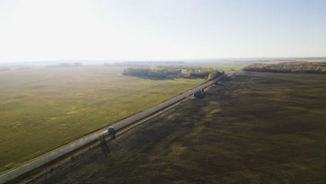 aerial view of car driving in the road passing by the agricultural fields.