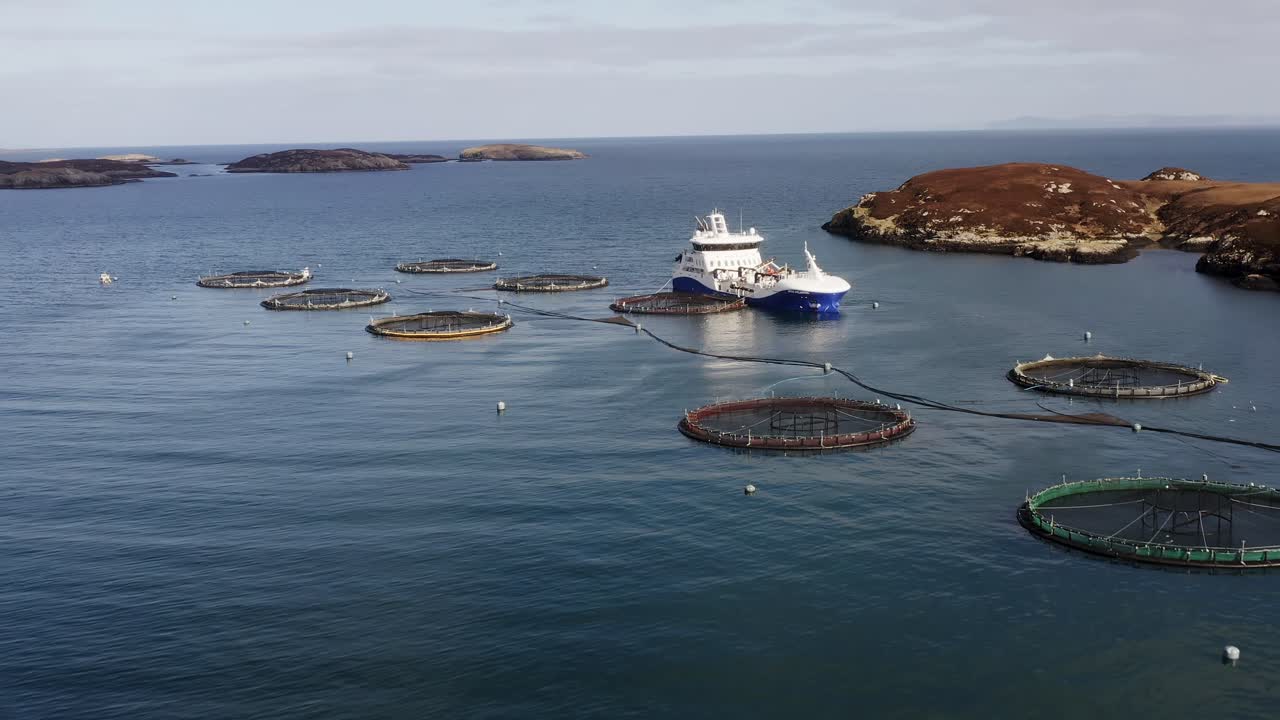 Ascending drone shot of a fish farm and a well-boat near the Isle of Uist