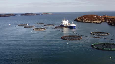 ascending drone shot of a fish farm and a well-boat near the isle of uist