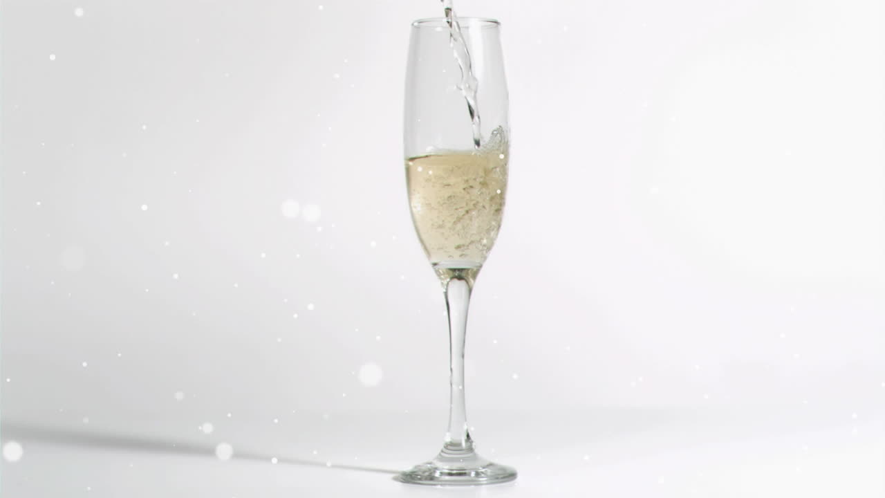 Animation of white specks falling over glass of champagne on white background