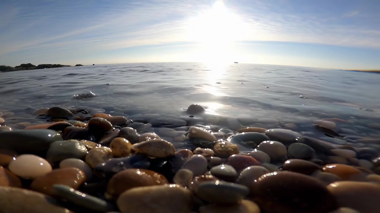 Ondas Suaves Lavando Seixos Lisos em uma Praia Ensolarada