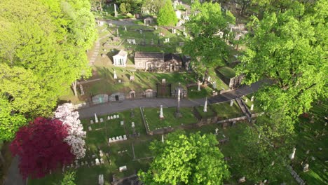Beautiful-lush-green-cemetery-with-tombstones-and-mausoleums,-aerial-view
