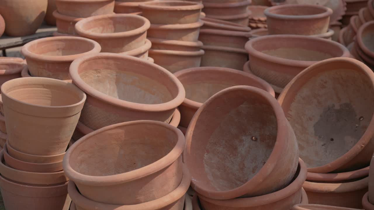 Un primo piano di vari vasi e fioriere in terracotta fatti a mano impilati in un mercato all'aperto di venditori ambulanti in India. Ideale per temi di giardinaggio e artigianato della ceramica