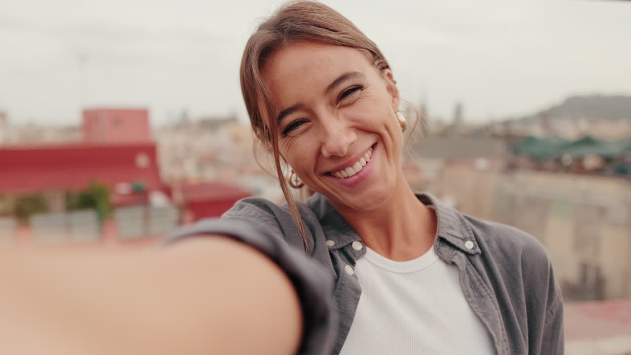 Joven feliz grabando un video selfie en la azotea de la ciudad