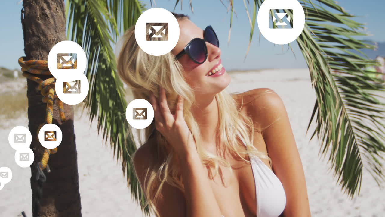 Animazione di icone di social media ed email su una donna sorridente in spiaggia