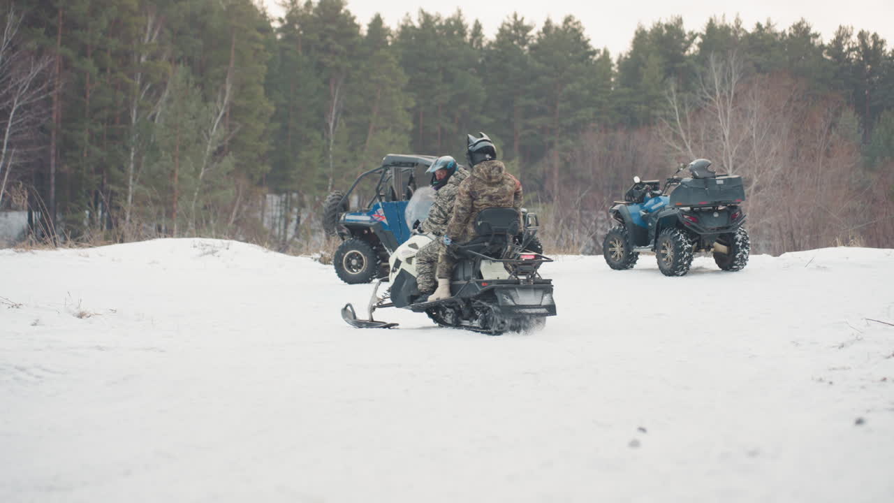 Convoglio si riunisce in una radura forestale innevata. Un team di motoslitte e UTV si raduna in uno spazio boschivo invernale. Un gruppo di piloti con veicoli da neve si raduna in una radura innevata circondata da pini.