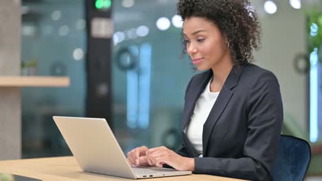 african businesswoman excited for success on laptop at work