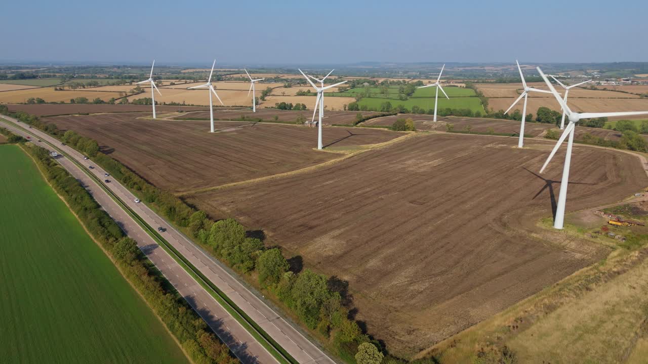 Aerial drone shot of large wind turbine and solar power plant renewable energy generation sunny day near Loughborough England UK