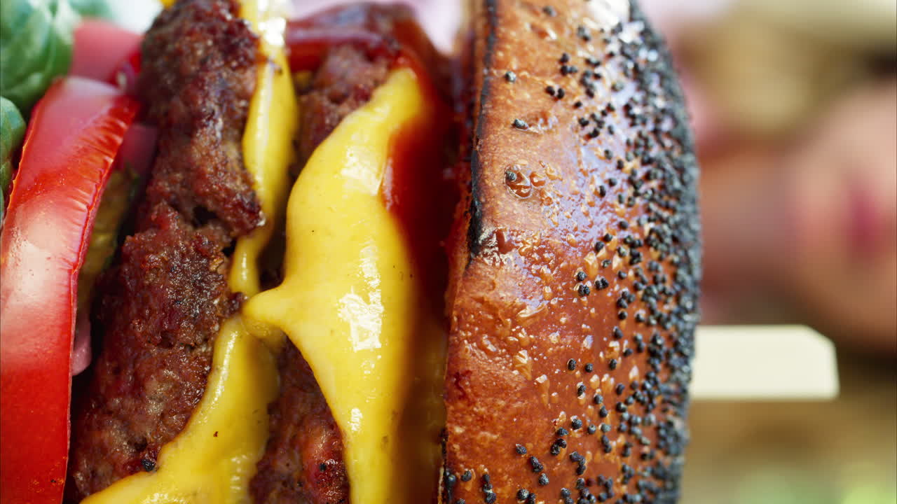 Close up of a big hamburger on a table at a restaurant. Vertical