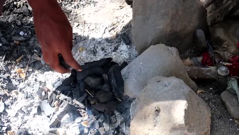 African-Datoga-tribe-man-adding-coal-to-the-ashes-while-other-blows-them-with-rustic-object