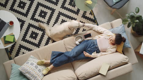 woman lying on sofa and petting dog