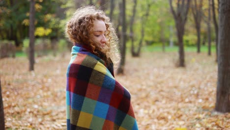 Lockige-Frau-Steht-Im-Goldenen-Herbstpark-Und-Bedeckt-Sich-Mit-Plaid