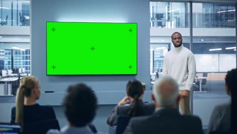 modern product presentation event: black businessman speaks, uses green chroma key screen wall tv. press conference for group of diverse multi-ethnic investors, digital entrepreneurs, businesspeople