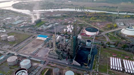 órbita-Aérea-De-Una-Refinería-De-Petróleo-Y-Su-Torre-De-Fraccionamiento-Con-Los-Tanques-Al-Fondo,-Entorno-Natural