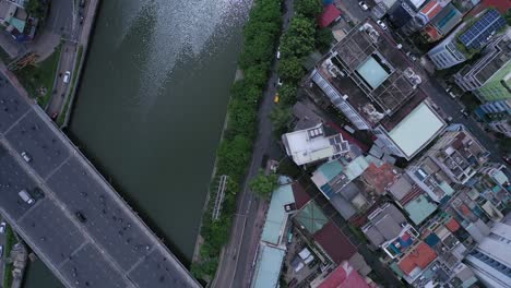 streets, traffic bridge and tree lined canal with buildings from top down aerial view