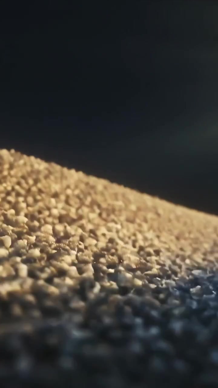 Video verticale: Cumulo di grano che si sposta e cambia colore sotto il cielo aperto mentre la luce del sole svanisce, i chicchi brillano