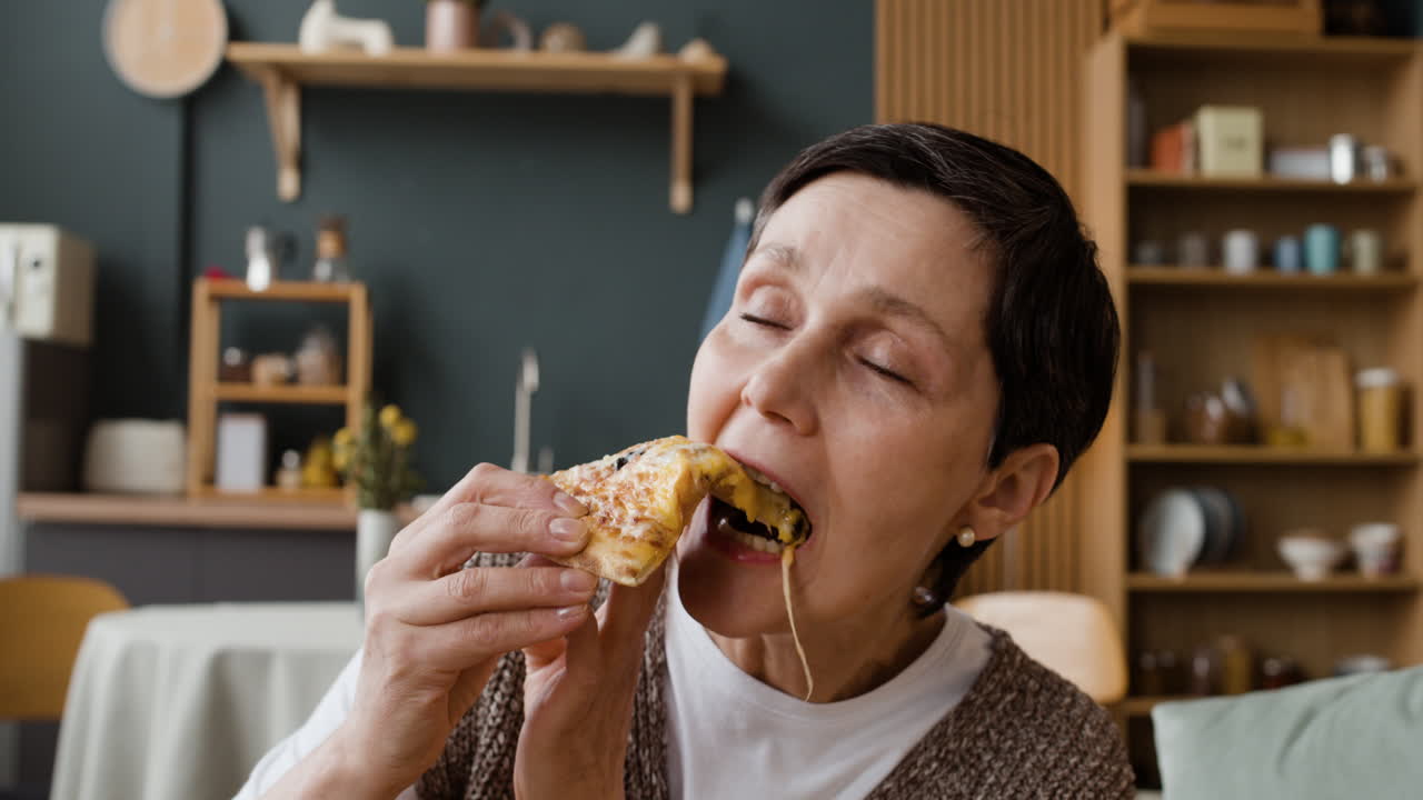 Woman Enjoying a Slice of Pizza with a Long Cheese Pull