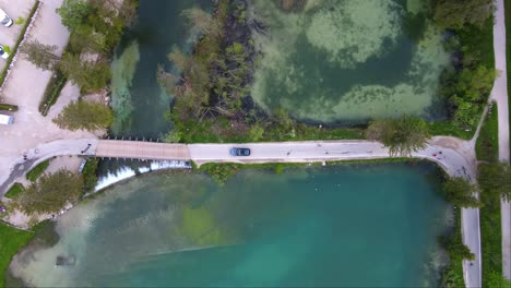 Top-shot-of-car-driving-on-bridge-near-Lake-Dobbiaco,-Toblacher-See