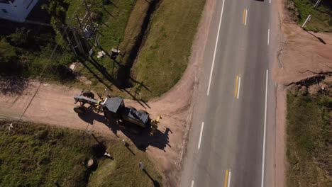 toma aérea de un vehículo rodante que se convierte en una carretera de obra al sol