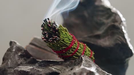 person holding palo santo wood stick in hand, aromatic palo santo burning on black background, smoke spreading around, slow motion video clip, high quality 4k close up footage. high quality 4k footage