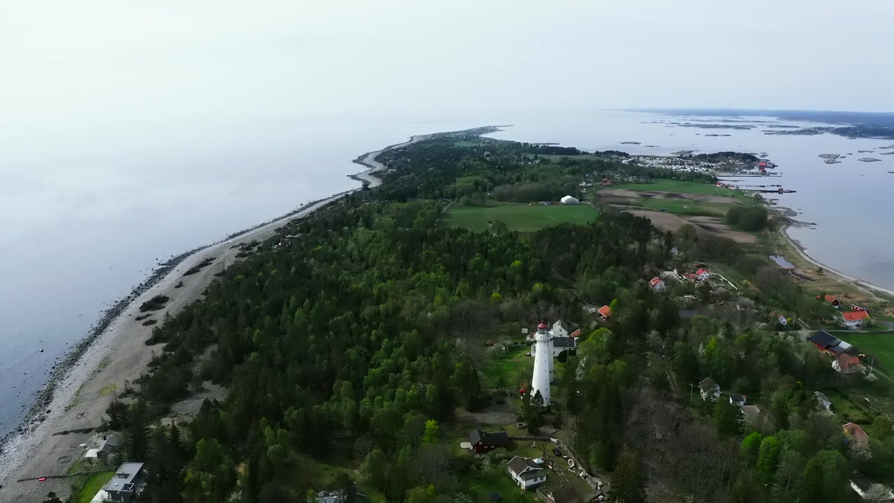 Vista aérea de farol numa península arborizada cercada por água