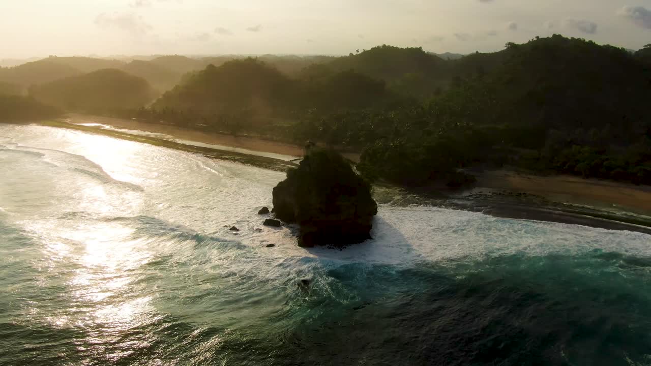 impresionante puesta de sol sobre siluetas de roca en la playa de asmara, java, indonesia, aérea