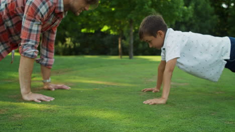 Man-and-boy-doing-push-ups-in-meadow.-Cheerful-father-and-son-training-together
