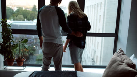 pareja mirando a través de la ventana en el dormitorio 4k