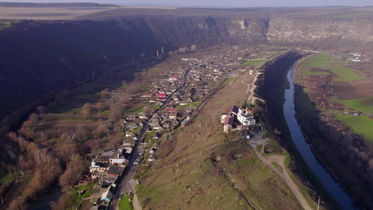 Barrido aéreo panorámico a la derecha desde las laderas de los acantilados hasta las llanuras aluviales, las espectaculares curvas del cañón y el asentamiento histórico en Orheiul Vechi, Moldavia