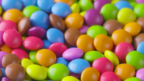 slow motion close-up of round colorful chocolate candies, dragee. rotation and fall multicolored chocolate candies