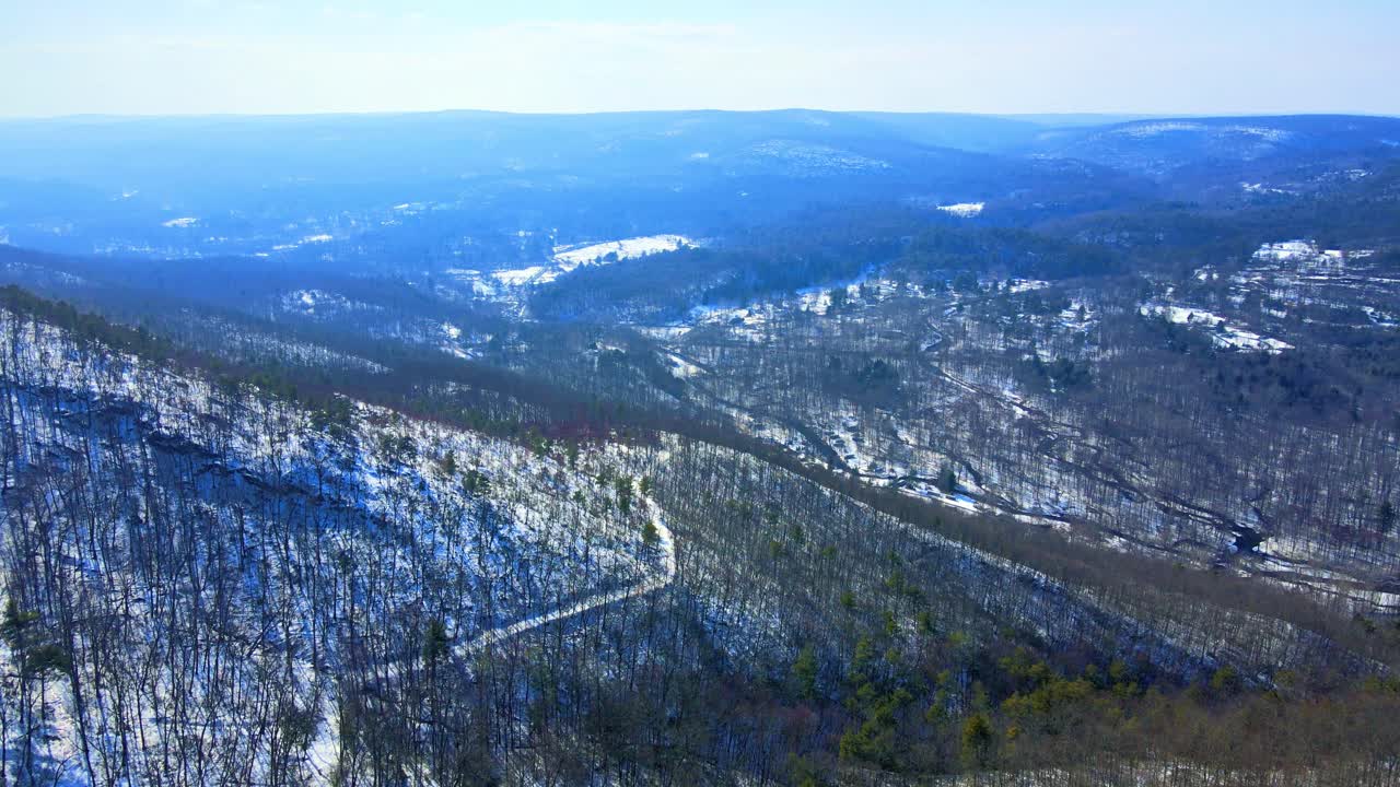 Aerial drone video footage of a snowy mountain valley during early spring with sunny blue skies