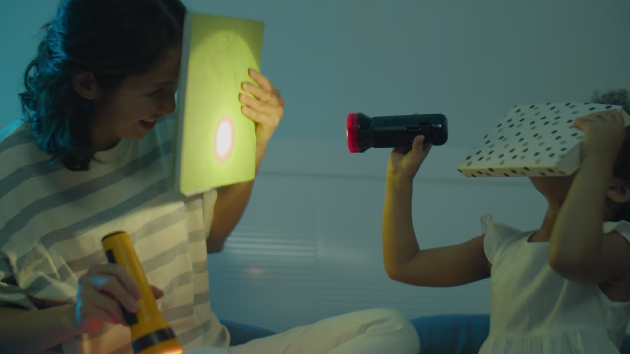 Joyful Little Girl and Mother Playing with Flashlights at Night